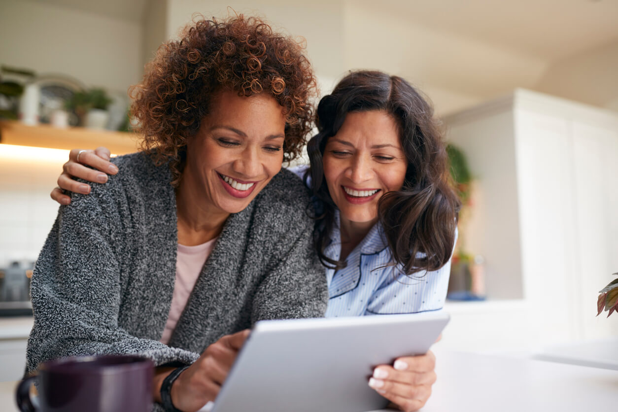 Two women looking at an iPad smiling