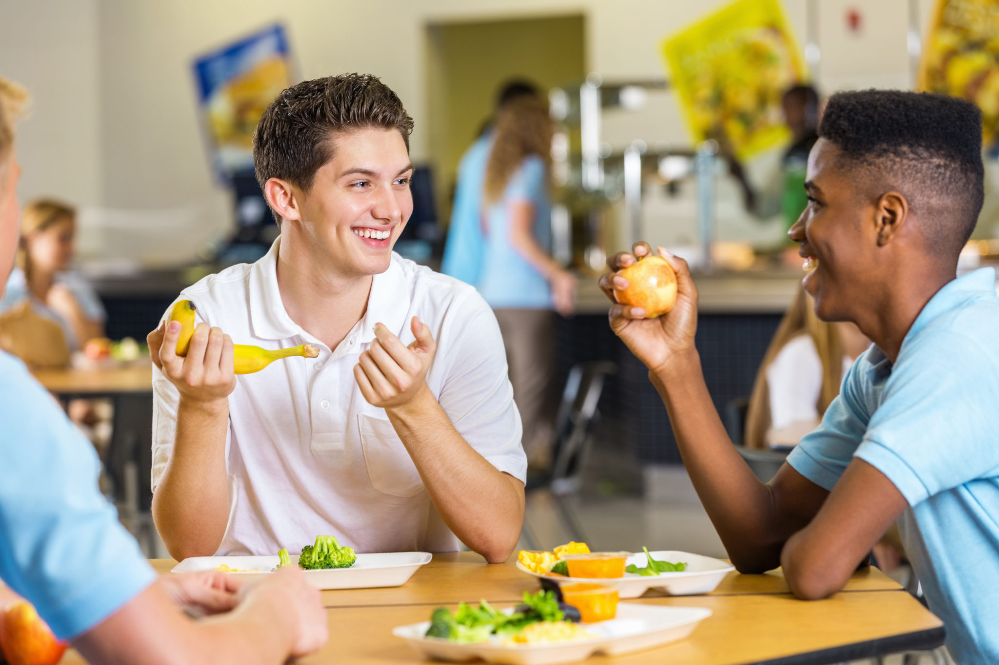 High school boys laughing together while eating lunch in cafeteria