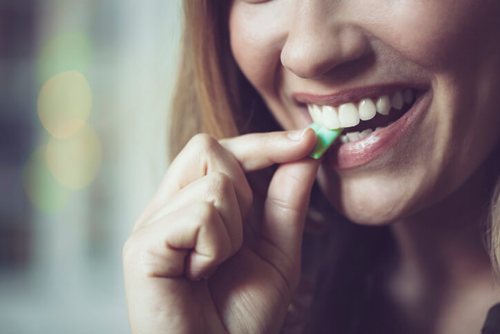 Woman putting chewing gum in her mouth