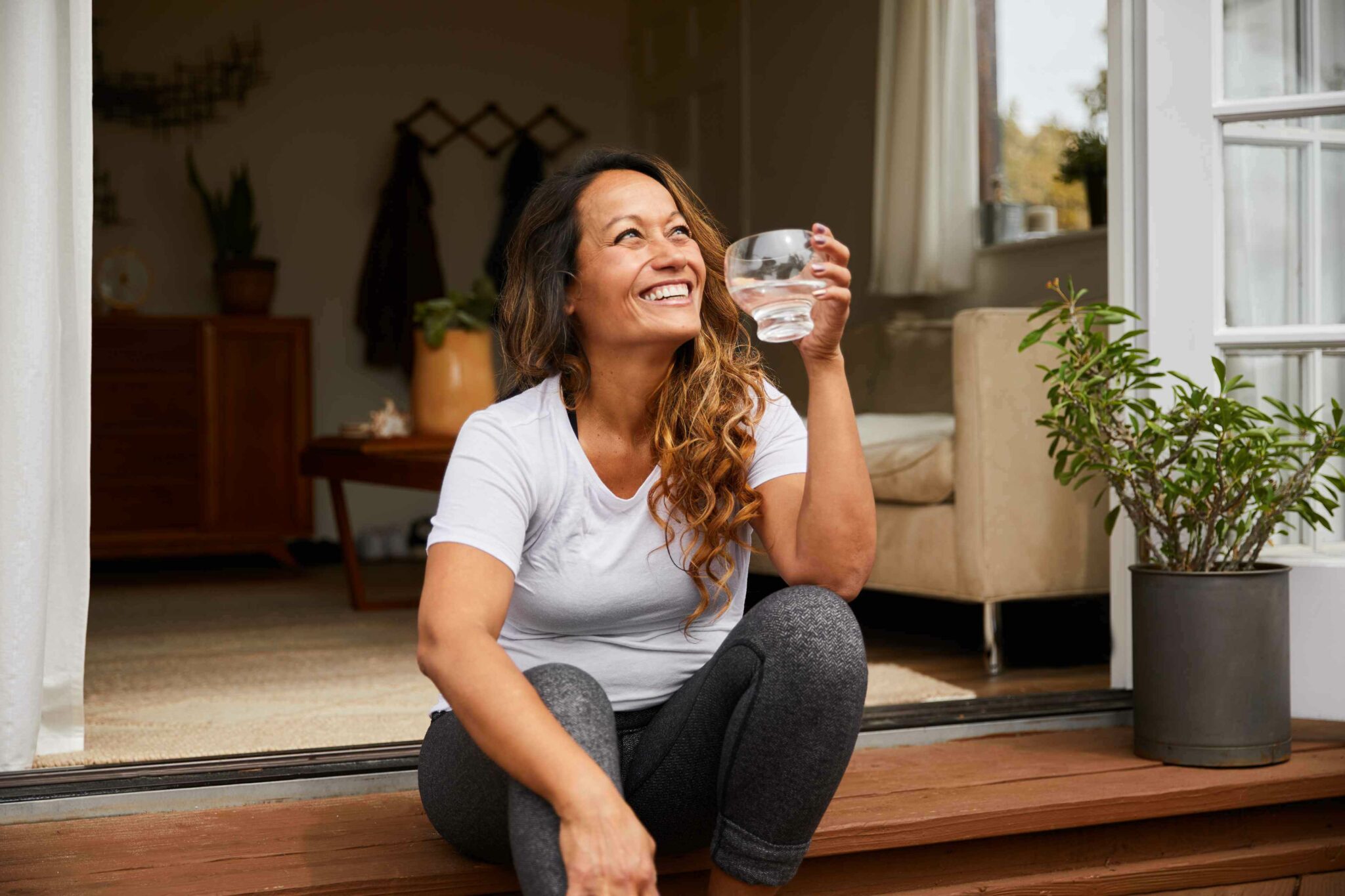 A woman drinking a glass of water on her deck.