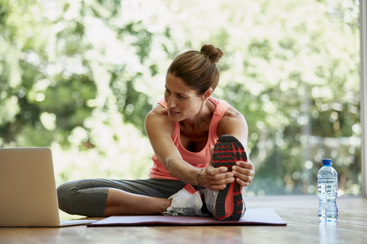 Woman looking at laptop while exercising at gym