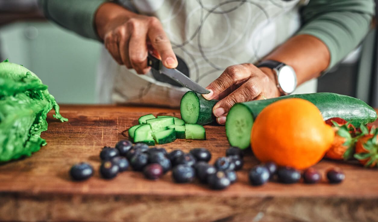 A person cutting healthy foods on a cutting board